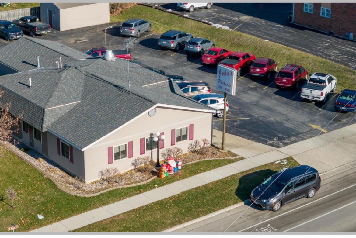 Jackie's Parkside from above — a low tan building on West Main Street with a full parking lot and a white roadside sign reading Jackie's Parkside, Fine Food